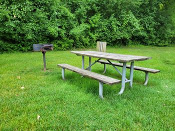 a picnic table and bench in a grassy area next to a grill